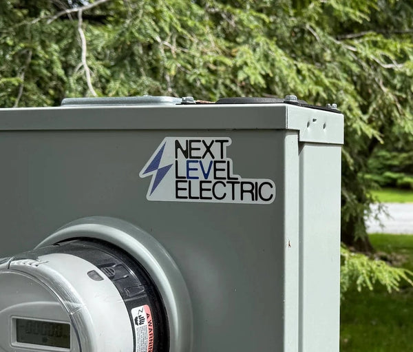 Electric meter box with 'Next Level Electric' branding in a residential area.