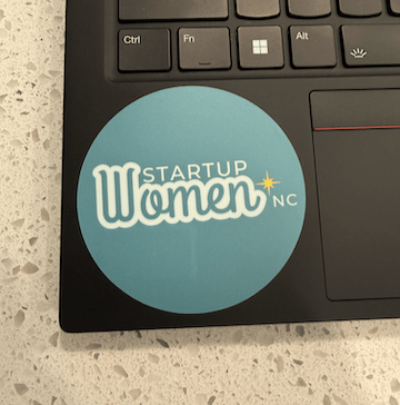 Laptop with a 'Startup Women NC' sticker on the keyboard