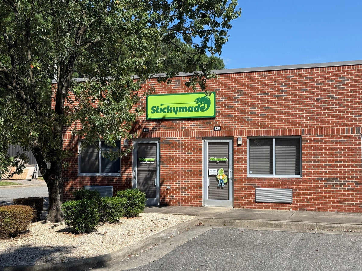 Brick building with a green sign on the side, surrounded by trees and clear sky.
